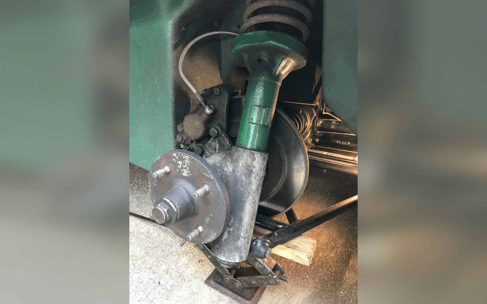 A wheel-off corner of a car showing coilover and brake assembly